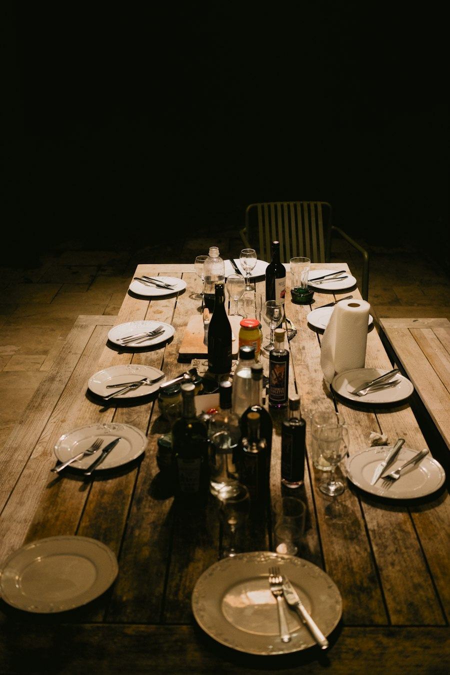 A long wooden table set for dinner in the evening